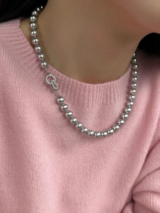 Detailed view of gray pearl necklace with zircon-encrusted silver clasp on a model neck