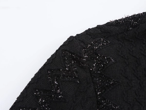 Detail of elegant black dress showing wavy embroidery with sparkling sequins and textures