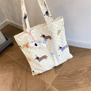 Detail of canvas tote bag featuring brown dachshund print and white plush puppy charm