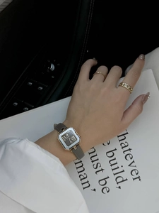 Primo piano di un orologio da donna vintage quadrato dorato con cinturino in pelle grigia