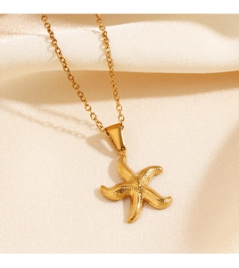 Gros plan d'un collier pendentif étoile de mer dorée sur tissu en soie beige