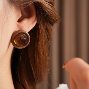 Close-up of retro round amber resin stud earrings worn by a model for a vintage look
