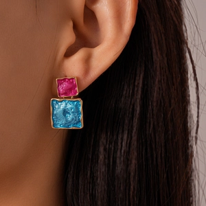 Detail of geometric square earrings featuring pink and blue enamel with hammered texture