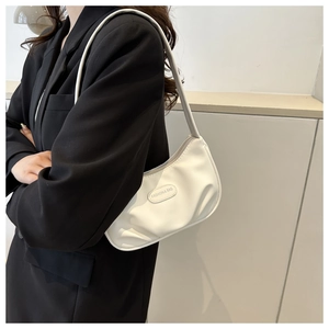 Détail d'un sac à bandoulière blanc plissé en forme de croissant avec logo gravé