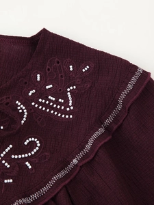 Detail of beaded embroidery and ribbed texture on dark burgundy linen-style shirt