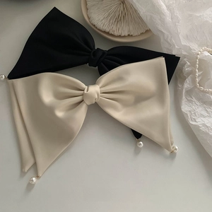 Close-up of fabric bow hair clips with elegant pearl charms in black and beige tones
