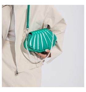 Detailansicht einer grünen Metallic-Muscheltasche mit Perlengriff an einem Model