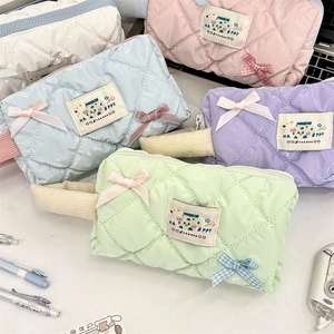 Close-up of quilted bow pencil cases in pastel colors with top zipper and corduroy handle