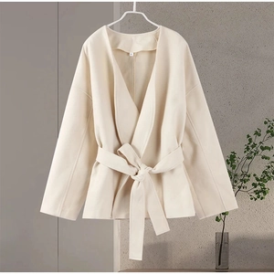 Detail shot of a cream V-neck wool jacket showing the soft texture and size S label on a hanger