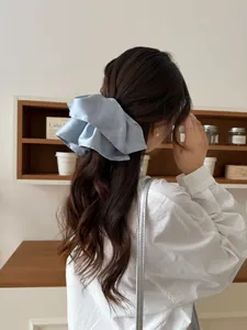 Close-up of light blue satin oversized bow hair tie with elegant silk-like pleats