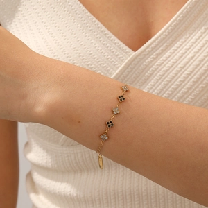 Elegant gold stainless steel bracelet with black enamel and zircon clover charms on a wrist
