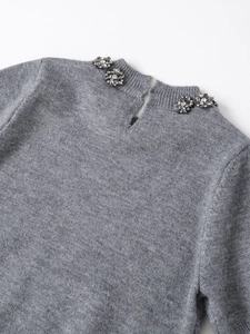 Detail of grey knit top featuring sparkling rhinestone floral clusters on the crew neckline