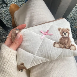 Detailed texture of quilted beige makeup bag featuring cute brown teddy bear patterns