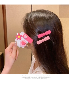 Detail of pink resin hair clips with flower and heart motifs on model's hair