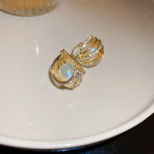 Gros plan de boucles d'oreilles géométriques dorées avec perles nacrées et strass brillants