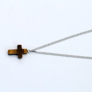 Detailed view of natural tiger eye stone cross pendant on a silver metal chain necklace