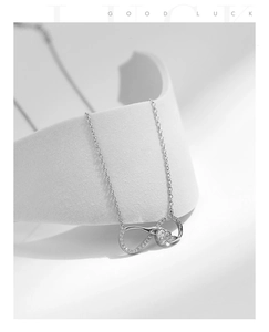 Close-up of S925 sterling silver Mobius infinity heart necklace with zircon on white stand