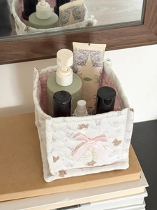 Close-up of quilted storage basket with cute bear print and pink bow decoration