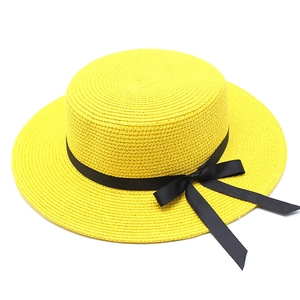 Détail du tissage d'un chapeau de paille jaune à sommet plat avec ruban noir