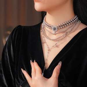 Detail of layered silver necklace with grey pearls and vintage dark gemstone pendant