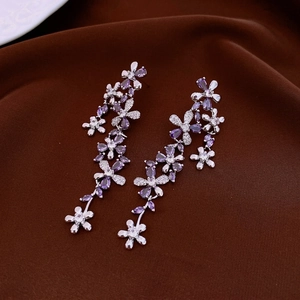 Silver flower tassel earrings with purple stones and diamonds on brown velvet background
