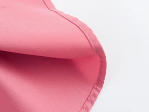 Gros plan de l'ourlet en tissu rose montrant les coutures et la texture de qualité
