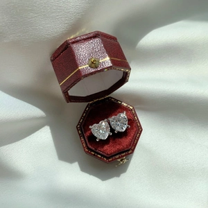 Macro shot of silver heart-shaped stud earrings featuring clear cubic zirconia in a red box