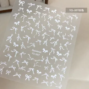Macro shot of white bowknot nail art stickers featuring varied ribbon designs on YO-007 sheet