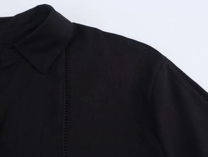 Detailed close-up of black linen shirt collar with decorative openwork stitching