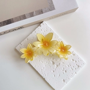 Detail of yellow flower hair claw clip with gradient petals and glossy resin finish