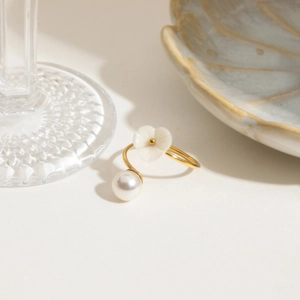 Detailed view of an adjustable gold ring featuring a white shell flower and a round pearl
