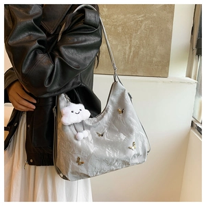 Detailed shot of grey pleated shoulder bag with metal butterfly and cloud plush pendant
