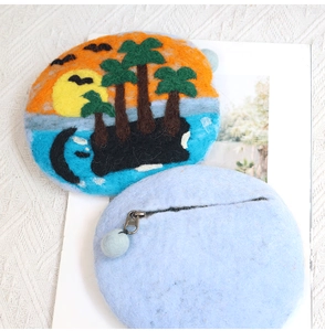 Detailed close-up of handmade wool felt coin purse with needle-felted island sunset scenery