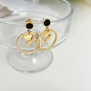 Elegant gold fox dangle earrings with black circular studs on clear glass pedestal