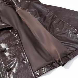 Detail der dunkelbraunen Glanzlederjacke mit Nähten, Knöpfen und dem Innenfutter