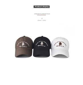 Detailed view of embroidered cartoon bear on cotton baseball caps in brown, black and white