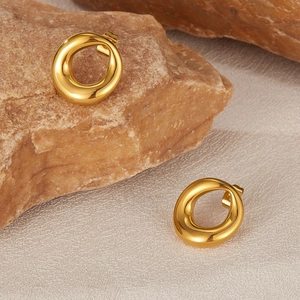 Detailed view of polished golden irregular round earrings on a natural stone base