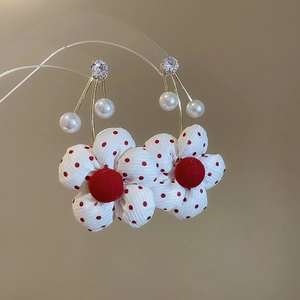 Macro shot of fabric flower earrings with red dots, white pearls, and gold finish hooks