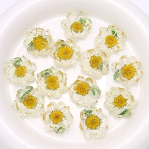 Transparent resin daisy flower pendants with yellow dried flowers in a white bowl