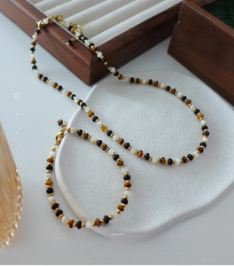 Detail of natural tiger eye stone necklace and bracelet set on a ceramic display tray