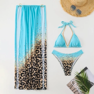 Flat lay of leopard print three-piece bikini set with sheer sarong and gold chain detail