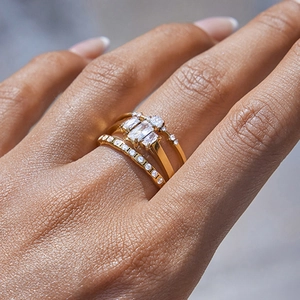 Close-up of stacked gold titanium steel rings set with rectangular white gemstones on hand
