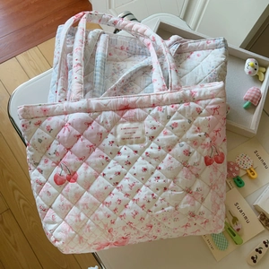 Detailaufnahme der gesteppten Tragetasche mit rosa Schleifen und Kirschmuster