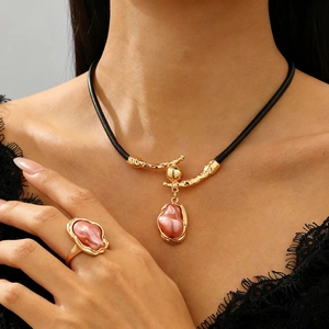 Dettaglio di set con collana e anello di perle barocche e dettagli dorati su cordino