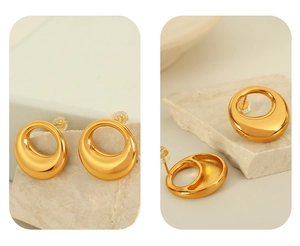 Detail of golden hollow O-shaped earrings with silicone plugs on stone background