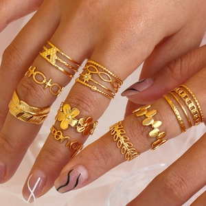 Close-up of gold stainless steel ring set with feather, floral, and geometric patterns