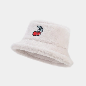 Close-up of red cherry embroidery and soft faux fur texture on the cream bucket hat