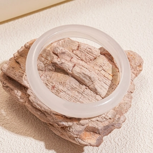 Detail of a semi-transparent pink resin bangle with a polished finish on textured stone