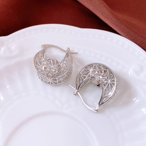Detail view of 18K gold plated hollow floral hoop earrings on a ceramic jewelry tray