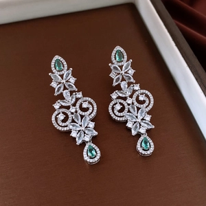 Detailed view of silver flower earrings with clear zircon and green teardrop gems